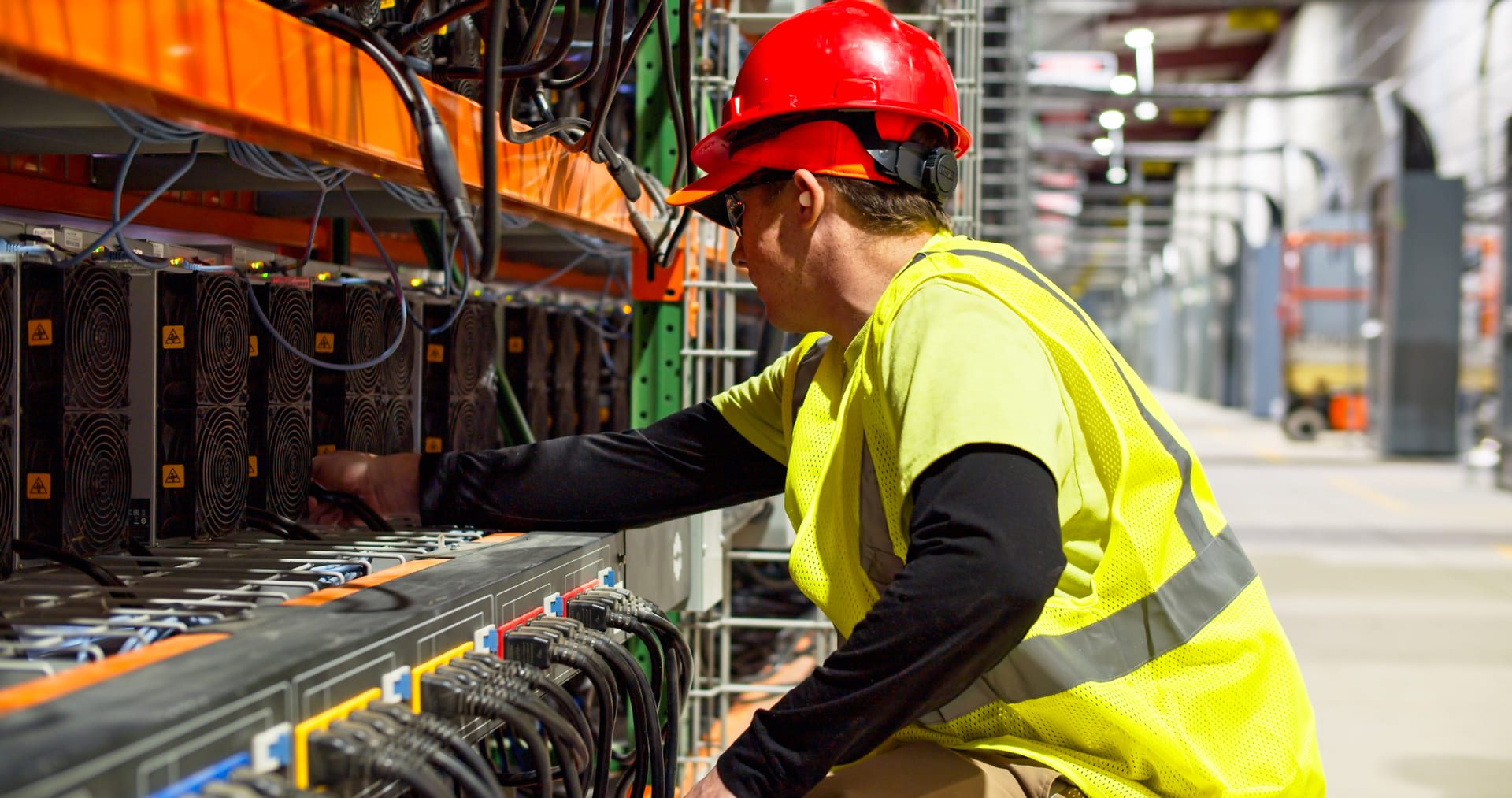 Technician in safety gear wiring a commercial data center AI project